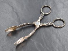 A pair of Victorian silver sugar serving tongs, having Apostles to the stems and handles, marks