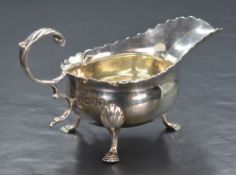 A Victorian silver sauce boat, having a lobed style rim, narrow spout opposed by a scrolling handle,