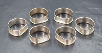 A set of six Elizabeth II silver napkin rings, having engine turned decoration and vacant