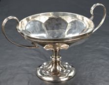 A late Edwardian silver pedestal bon-bon dish, having two c-curve handles with lobed body, raised on