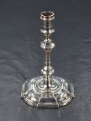 A small George II silver candlestick, having a knopped stem raised on a moulded rounded square foot,