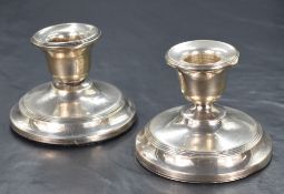 A pair of George V silver stout candlesticks, of traditional form having step moulding decoration,