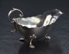 An early George V silver sauce boat, with Chippendale style rim, narrow spout opposed by a scrolling