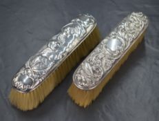 Two silver mounted clothes brushes, one with embossed decorative scroll work and birds, the other