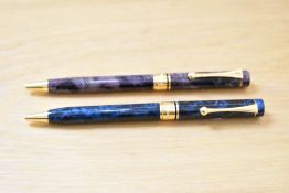 Two L'Plume ballpoint pens one blue the purple with gold trim