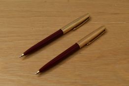 Two Parker 45 ballpoint pens in red with rolled gold cap. Slight dent to one cap
