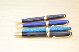 Four L'Plume ballpoint pens one blue, a grey, a black and turqoise with gold trim. The black is