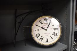 A reproduction Kensington Station clock with integral bracket, having Roman hours, 26cm diameter
