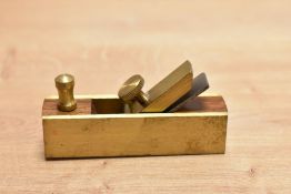 A novelty brass mounted model of a woodworking plane, measuring 8cm long