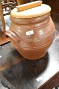 A traditional earthernware egg crock , with wooden lid