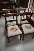 A set of four 19th Century Regency design rail back dining chairs having later woolwork seats