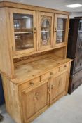 A traditional stripped pine dresser having glazed upper section , three frieze drawers and double