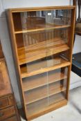 A vintage teak double height bookcase, having sliding glass doors, approx. height 145, width 69cm