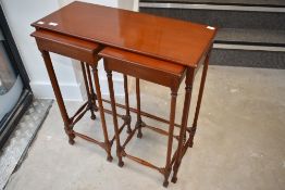 A reproduction mahogany shallow nest of two under one occasional table having turned frames