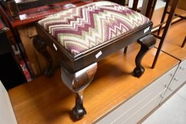An early 20th Century mahogany footstool having ball and claw feet