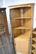 An Ercol mid stain corner shelf with cupboard under