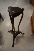 A modern hardwood plant stand having shaped trefoil supports and applique detailing, height