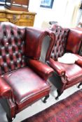 A pair of oxblood leather wingback armchairs