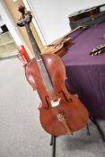 A traditional Cello , no visible label, on stand, with two bows
