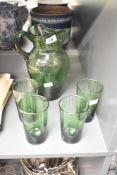 A vintage hand blown green glass pitcher with pinched spout, sold alongside four matching green
