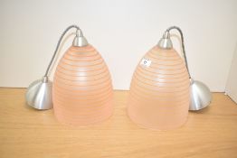 A pair of late 20th century glass pendent lights with circular orange swirl design, modern fittings,