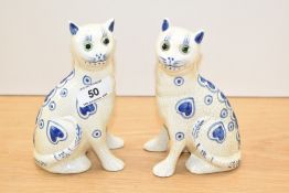 A pair of Galle style pottery seated cats, crackle glazed and decorated with blue hearts and dots,