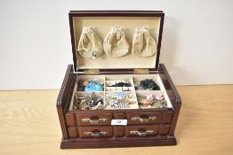 A wooden jewellery box, having cream lining, containing a collection of costume jewellery
