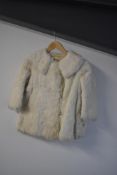 An early twentieth century childrens fur coat, in white-beige, probably rabbit. Has some staining to