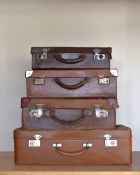 Four antique and vintage hard suit cases, in brown leather, sized incrementally from 22x14x7' down