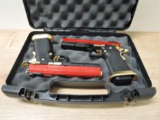 A pair of Armorer Works HX1004 Hi-Capa Split Side Gas BB Airsoft Pistols in red and gold, in carry