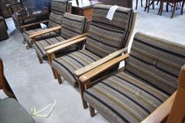 Three vintage teak framed easy chairs, with upholstery label for Ercol , and a similar rocking