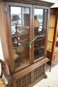 A mid to late 20th Century oak bookcase having glazed top with lower cupboard having cushion