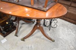 An early 20th Century Regency revival oval dining table, with extending leaf