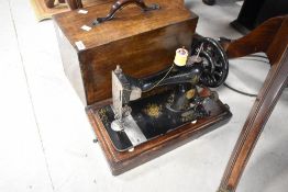 A 19th Century Singer hand cranked sewing machine having wooden case