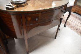 An early 20th Century bow fronted sideboard having square tapered legs on spade feet