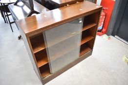 An early 20th Century oak low bookcase, having sliding glass doors, dimensions approx. W86 D25