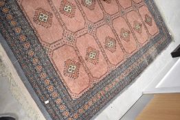A Persian style rug having pink ground with grey/blue border, approx. 195 x 130cm