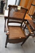 A vintage stained frame commode chair having bergere back and seat