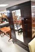 An early 20th Century mahogany mirror door wardrobe, having drawer base