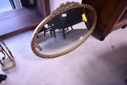 A traditional gilt frame wall mirror of oval form, approx. 72 x 47cm, with swag and bow decoration