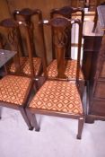 A set of four Edwardian mahogany dining chairs, the shaped top-rails with stipple craved ribbon