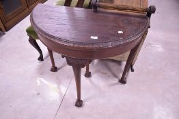 A Victorian mahogany demi-lune card table, of traditional design with moulded and carved foliate