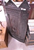 A period oak corner cupboard being heavily carved in the renaissance style