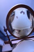 A reproduction mahogany dressing table top swing mirror, of oval form, pivoted between turned