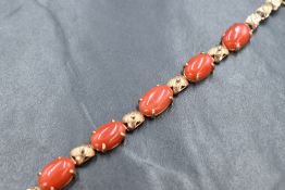 A yellow metal articulated bracelet stamped 18K having four coral set panels interspersed by