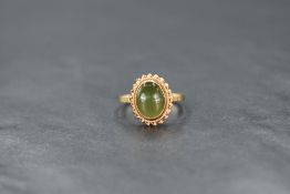 A 9ct gold green serpentine oval cabochon ring in a collared mount with twist wire decoration,