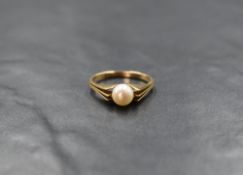A pearl solitaire ring having triple point split shoulders on a yellow metal loop, marks worn,