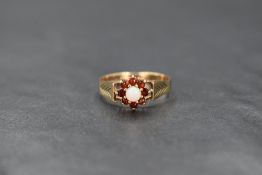 A 9ct gold opal and garnet cluster ring, the central opal cabochon with an eight round cut garnet