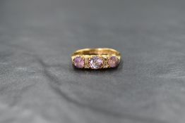 An 18ct gold three stone amethyst ring interspersed by 2 pairs of diamond chips, all in an