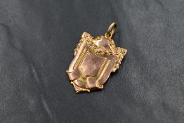 A 9ct gold shield pendant, the vacant shield having floral swag surround, 6.5g
